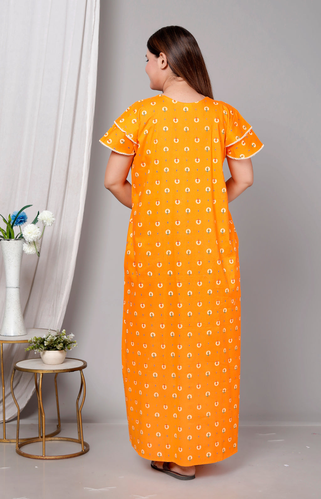 Woman wearing an orange dress with a white pattern in a minimalistic setting.
